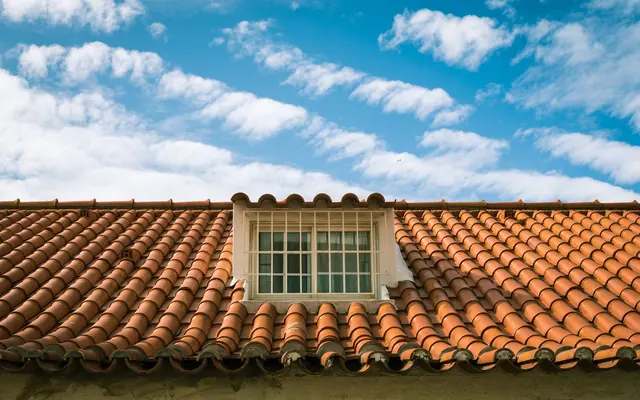 Terrakottafarbene Dachziegel und ein Dachfenster im Sonnenlicht