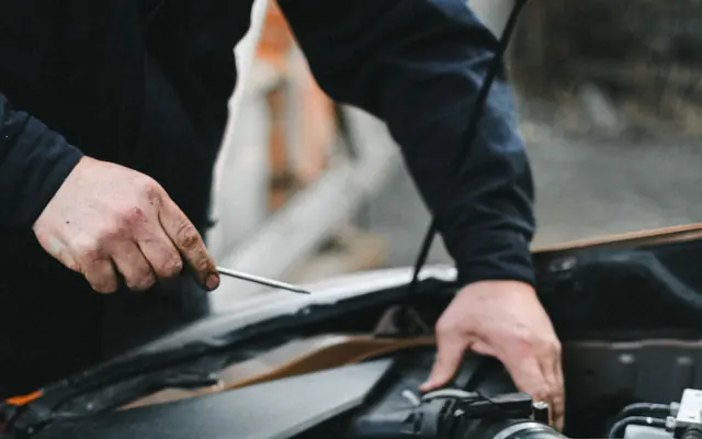 Hände arbeiten mit Werkzeug an einem Fahrzeugmotor