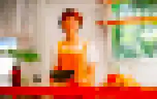 Eine lächelnde Frau mit Schürze an einer Cafétheke mit Gebäck