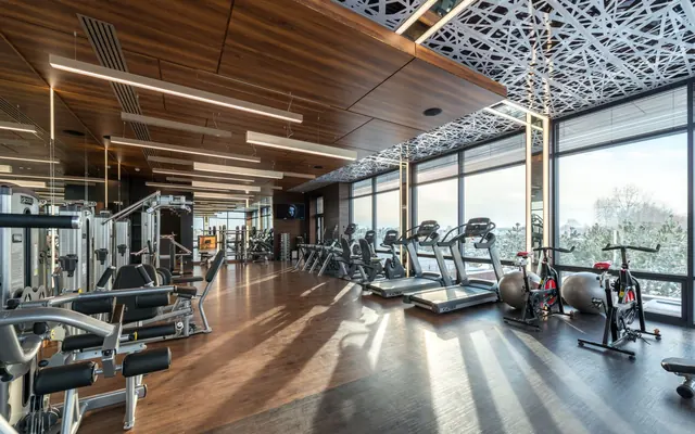 Ein heller Fitnessraum mit Geräten und großen Fenstern