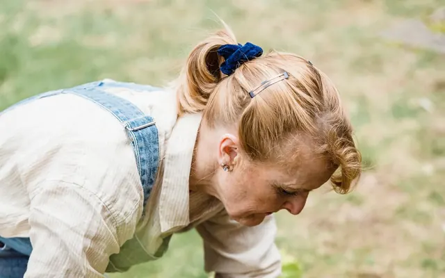 Eine Frau pflanzt mit Handschuhen Setzlinge in die Erde