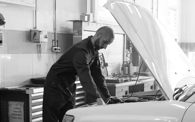 Ein Mann im Arbeitsanzug beugt sich über einen offenen Motorraum