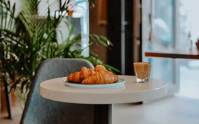 Ein Croissant und ein Glas Kaffee auf einem Cafétisch